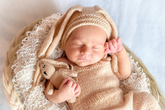 Baby das friedlich schläft mit einem Hasen in der Hand in einem Nest. 