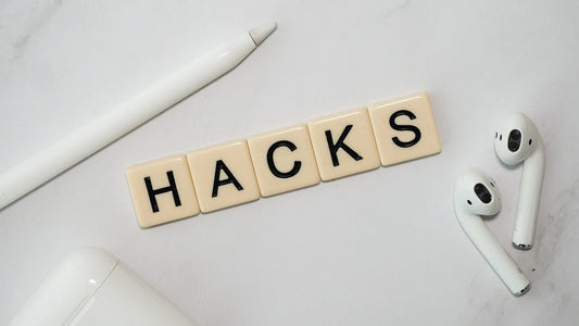 Schreibtisch-Szene mit weißen Kopfhörern, einem Eingabestift und Scrabble-Buchstaben, die das Wort ‚HACKS‘ bilden – Symbol für Business-Tipps und smarte Strategien.